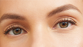 A close-up shot of a woman with brown eyes wearing mascara.